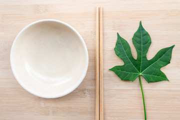 Ceramic plate with chopsticks mock up on wooden table background with copy space for text. Creative layout with food concept.