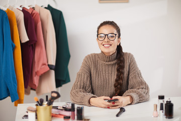 Portrait of smiling young woman looking at camera while filming video for beauty and lifestyle channel, copy space