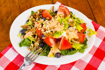 Large Mixed Salad with Thousand Island Dressing on PicNic Table with Red Plaid Tablecloth