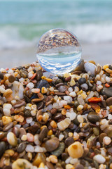 Glass round ball on the beach reflects the sea in summer