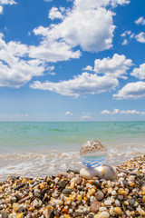 Glass round ball on the beach reflects the sea in summer