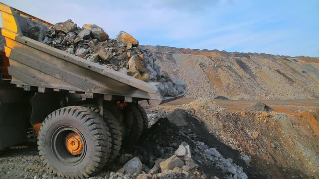 Heavy Yellow tipper truck on the quarry unloads earth and gravel