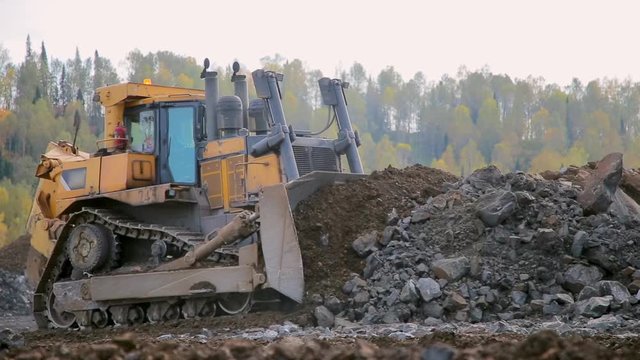 Yellow tracked bulldozer moves your bucket stones