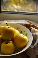 Natural yellow apples in a plate on a windowsill, organic fruits.