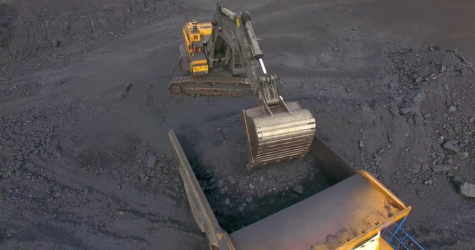 Aerial view from drone excavator loads coal into a dump truck