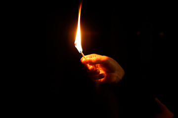 mano sujetando una cerilla encendida sobre fondo oscuro negro  IMG_4943-as19
