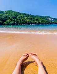 Fototapeta na wymiar Feet resting in Majahua's beach in Acapulco