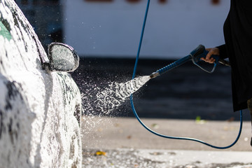 Close up detail of wash cleaning with foam on car at carwash station