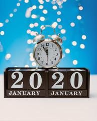 new year 2020 concept, alarm clock with the year 2020 written on wooden blocks