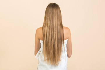 Obraz premium young woman with long flowing hair on a beige background