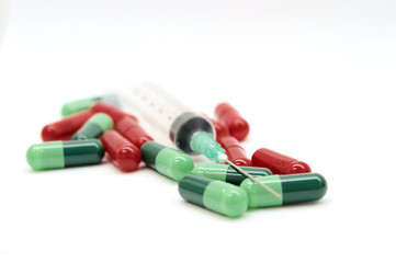 Green capsules red capsules and a syringe isolated