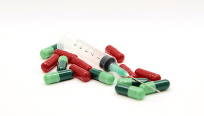 Green capsules red capsules and a syringe isolated