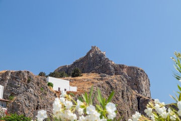 View at the acropolis of Lindos on Greek island Rhodes with white flowers in the foreground