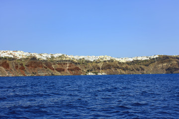 Wybrzeża greckiej wyspy Santorini z usytuowanymi na klifach miasteczkami - obrazy, fototapety, plakaty