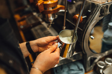 Fototapeta na wymiar Close up view Barista steaming milk in metal pitcher. Barista making coffee.