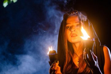 Young girl in a long black coat fire night.