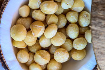 A close-up of coconut full of delicious raw macadamia nuts on wooden table