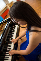 Elegant young woman playing a piano in a studio