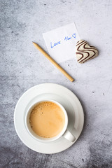Obraz na płótnie Canvas A declaration of love, zero waste pen, heart gingerbread, coffee mug on a gray background. Top view, vertical format