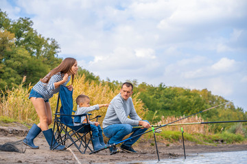 A happy family spends time together they teach their son to fish.