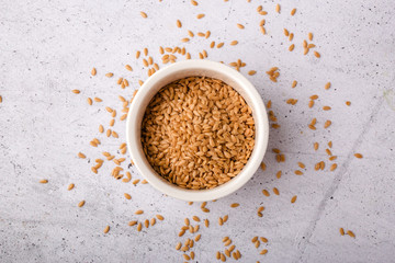 Brown flax in a white bowl on a gray background