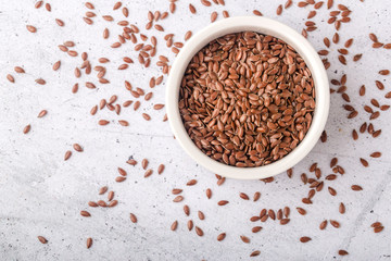 Brown flax in a white bowl on a gray background