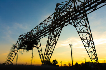 overhead crane at the railway station. Crane silhouette on sunset background. Heavy industry concept.