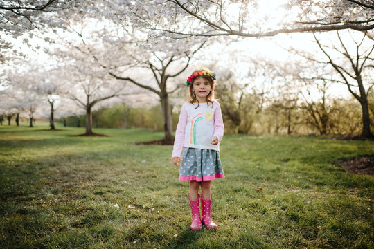 girl stands amongst cherry blossoms