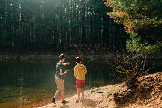 stock photo of boys fishing in beautiful emerald lake