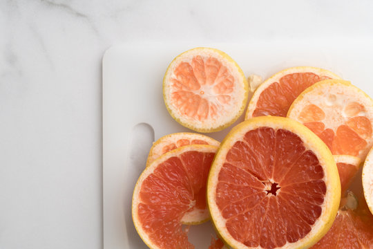 Citrus fruit on a white marble tabletop and cutting board