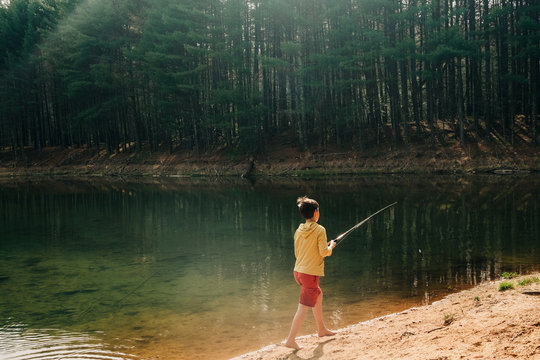 stock photo of boy fishing in beautiful emerald lake