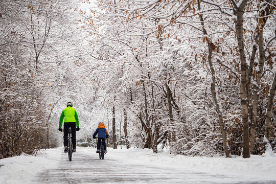 A father and his son ride a bikes in a winter park