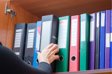 girl hand takes a folder from the shelf