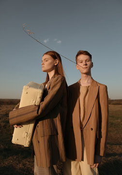 Siblings with suitcase in field