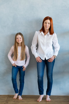 Young Beautiful Mom With Her Daughter Wearing Blank Gray T-shirt And Jeans Posing Against Rough Concrete Wall