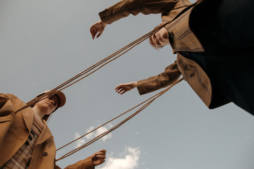 Twins playing with rope against gray sky in countryside