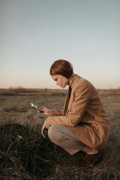 Young woman examining dirt pile