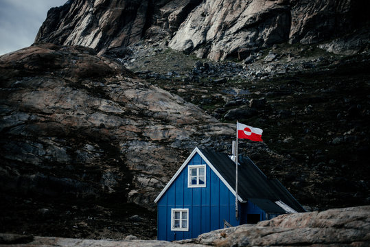 House with waving flag under rocky cliff