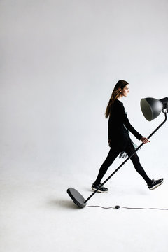 Fashion portrait of a girl walking with black lamp in studio