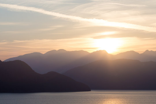 A sunset over layered mountains on the coast