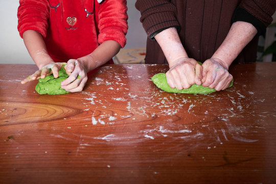Grandmother and grandson making dumplings together at home, close-up