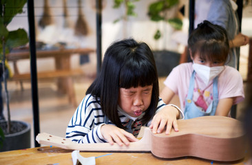 Asian children are learning to make ukulele in vacation