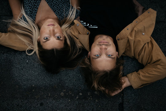 Overhead view of young man and woman lying on blacktop