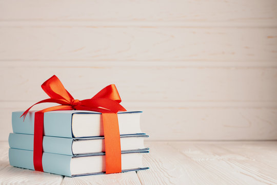A stack of three books tied with a red ribbon with a bow and copy space: the concept of a good book - a good gift
