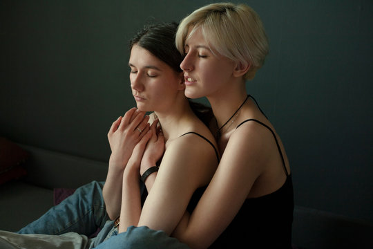 two lesbian girls embraced and closed their eyes against a neutral background
