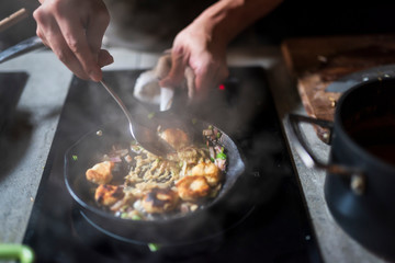 Man cooking delicious food in frying pan on electric stove