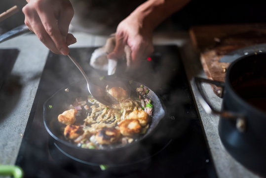 Man cooking delicious food in frying pan on electric stove