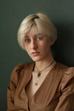 portrait of a beautiful blonde girl with short hair on a neutral background looking into the camera