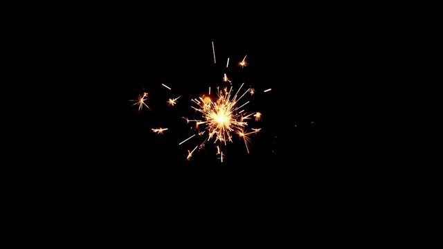 Static shot of a yellow and orange sparkler from above with a black background.
