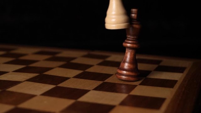 White chess piece overthrows a black chess piece.